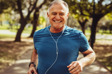 Upper body of a man running on a trail wearing headphones.