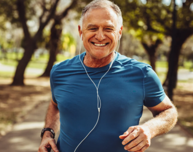 Upper body of a man running on a trail wearing headphones.