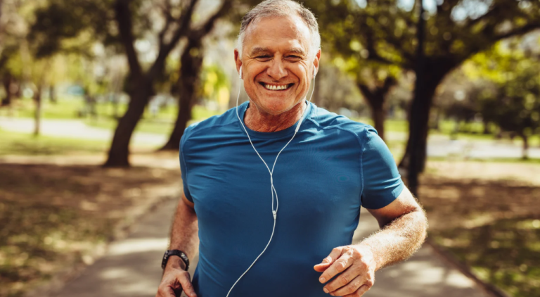 Upper body of a man running on a trail wearing headphones.